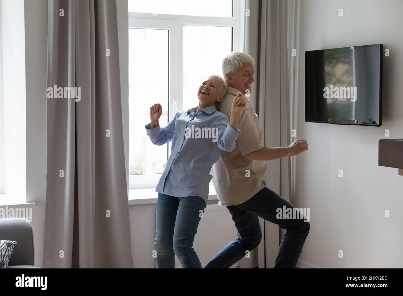 Glückliches reifes Paar, das gemeinsam im Wohnzimmer zu Musik tanzt Stockfoto