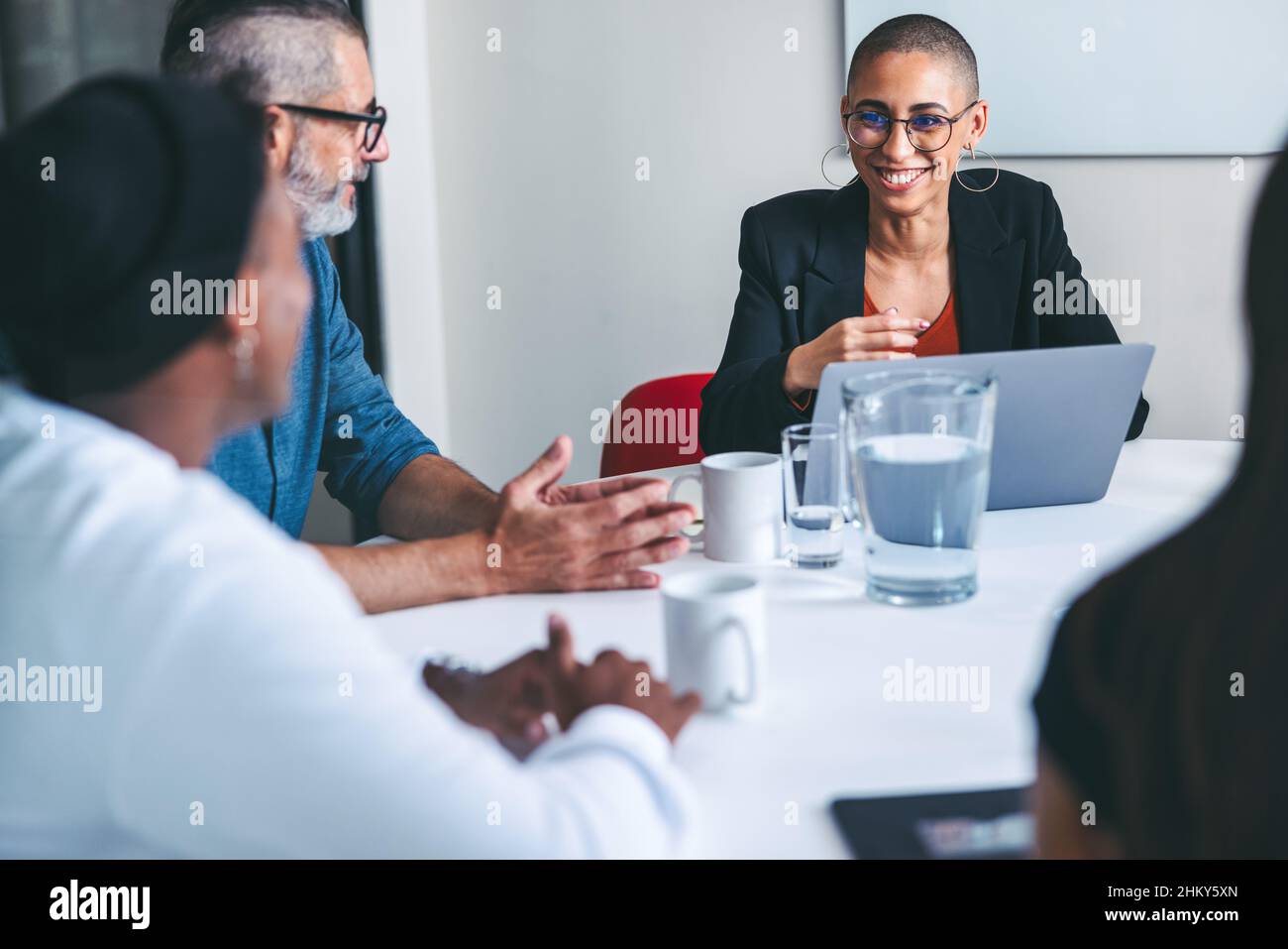 Verschiedene Geschäftsleute, die sich in einem Büro einfinden. Gruppe erfolgreicher Geschäftsleute, die während ihrer morgendlichen Besprechung an einem modernen Arbeitsplatz lächeln. Stockfoto