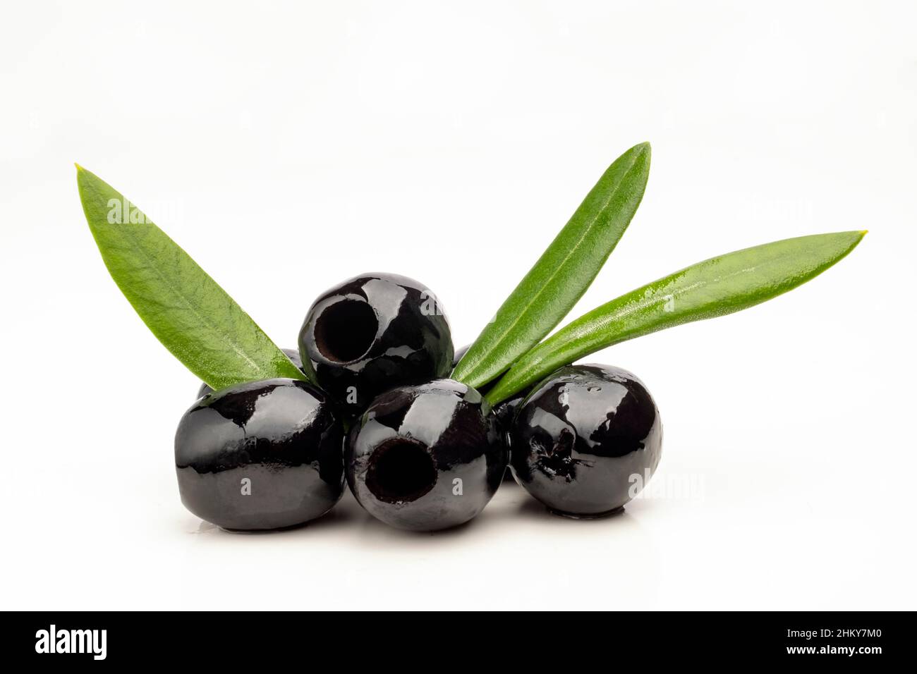 Schwarze Oliven mit Olivenblättern auf weißem Hintergrund Stockfoto