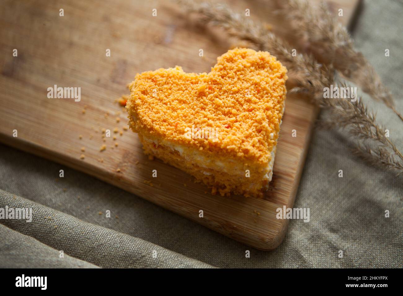 Am Valentinstag Dessert-Herz-Form orange Karottenkuchen auf ruhigen braunen Hintergrund. Minimalistisches Image Stockfoto