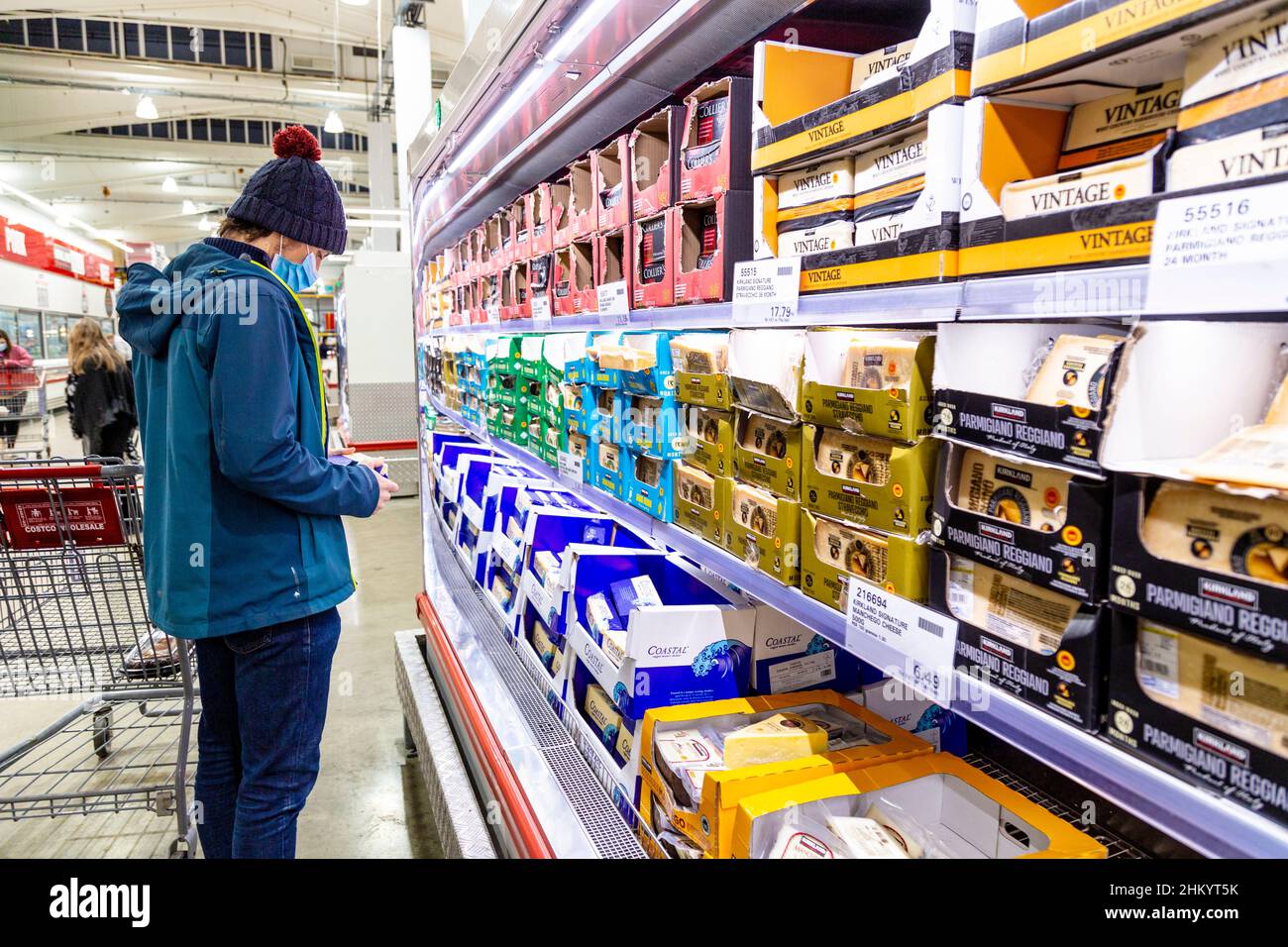 Mann mit Gesichtsmaske, der die Preise in einem Supermarkt nach der Coronavirus-Pandemie, der steigenden Inflation und der Lebenshaltungskrise betrachtet Stockfoto