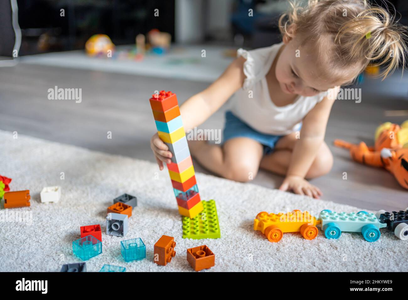 Kaukasisches Kind ein kleines Mädchen spielt zu Hause im Konstrukteur. Pädagogisches Spielzeug für Kinder. Stockfoto