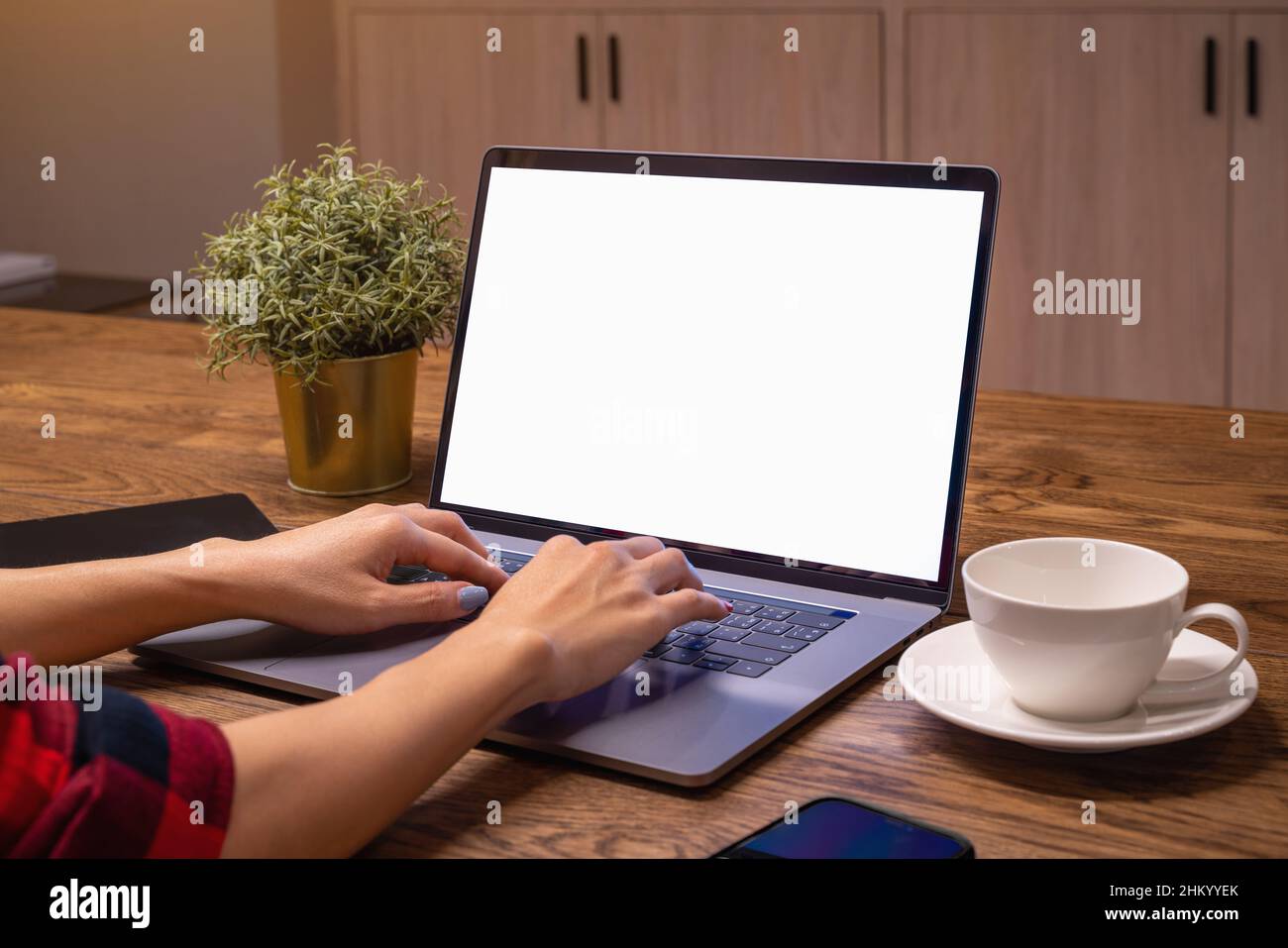 Frau, die auf einem Laptop mit weißem Bildschirm arbeitet. Arbeiten Sie von zu Hause aus. Stockfoto