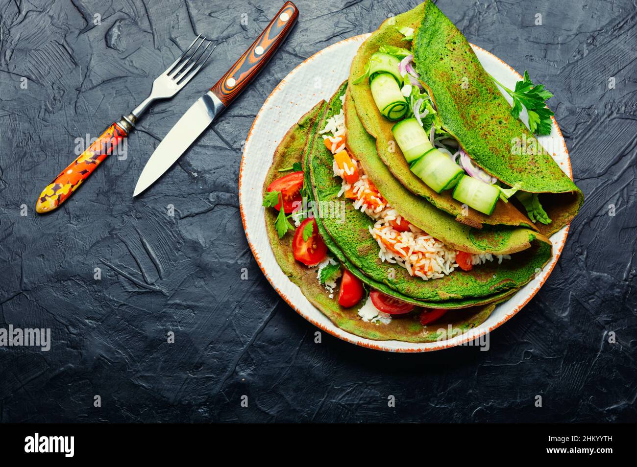 Pfannkuchen mit grünem Spinat, gefüllt mit Reis und Gemüse. Stockfoto