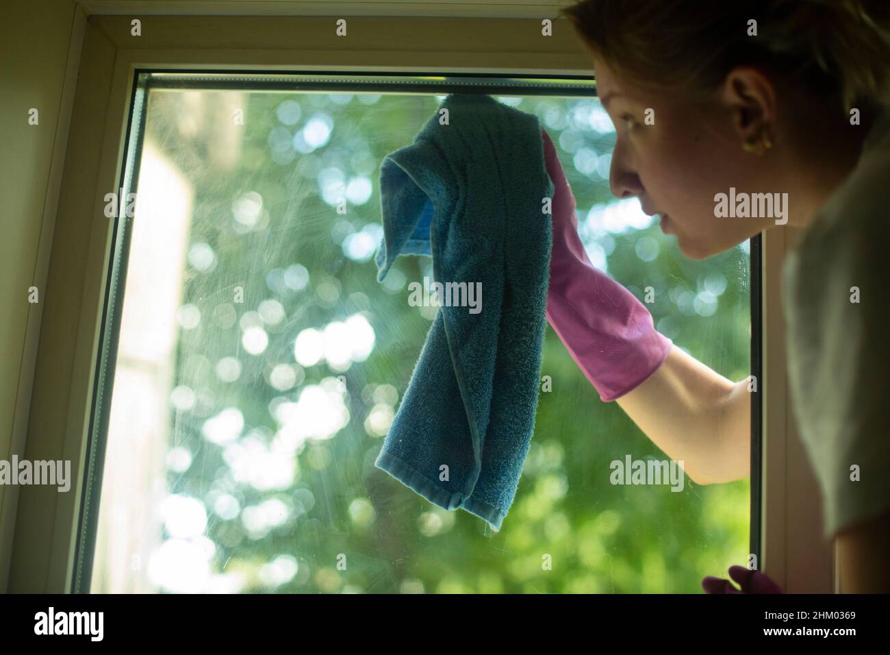 Das Mädchen wäscht das Fenster. Eine Frau hält einen Lappen in der Hand, um den Staub abzuwaschen. Das Mädchen putzt das Haus. Stockfoto