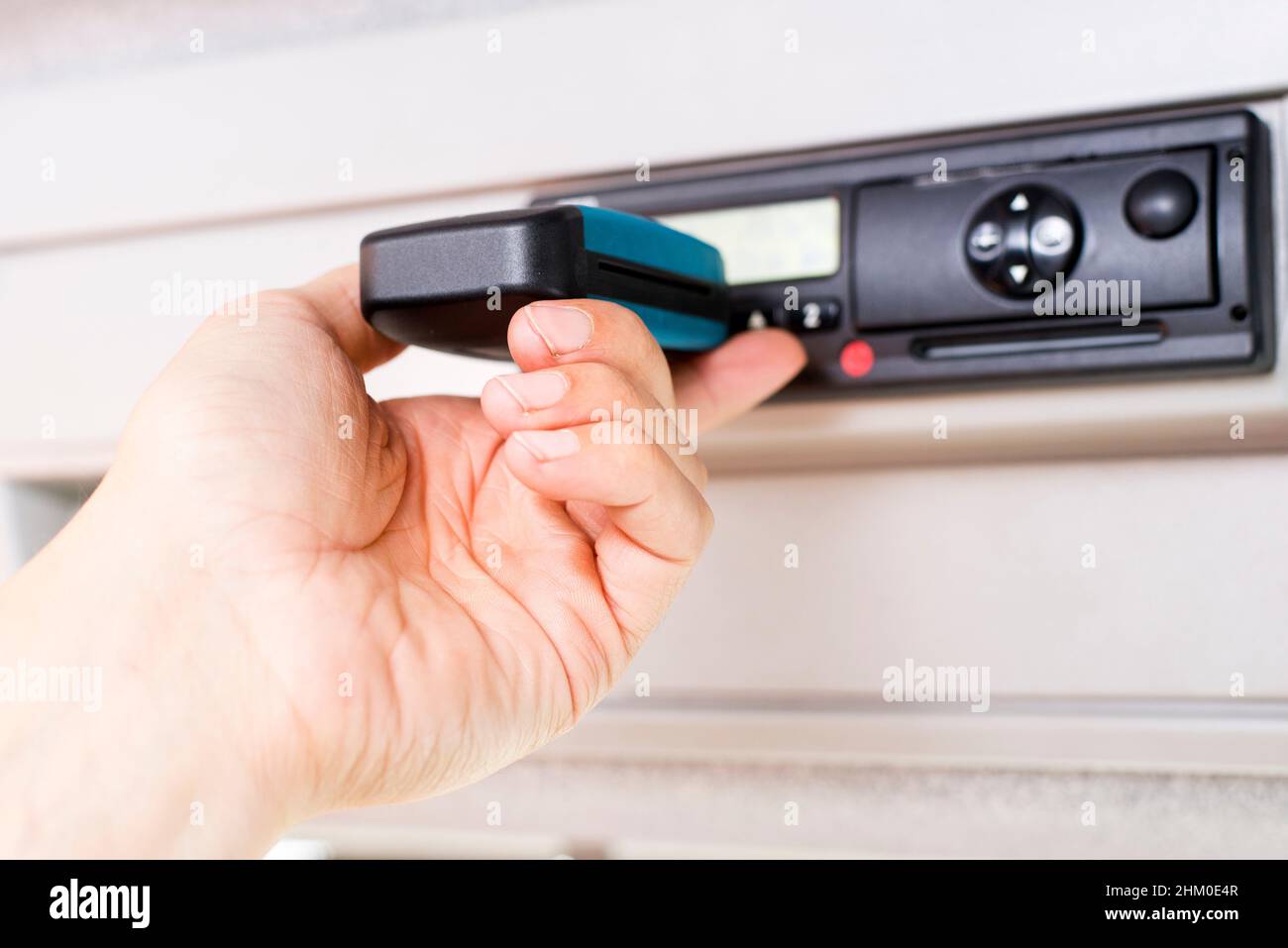Fahrer mit digitalem Fahrtenschreiber und isoliertem weißen Bildschirm. Tachograph herunterladen. Stockfoto
