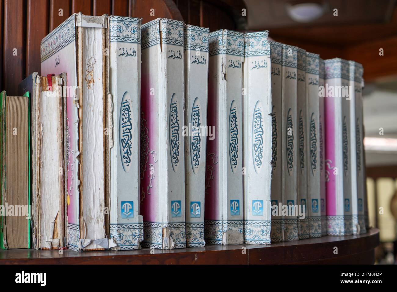 Die Sammlung des Korans und der Hadith in der Bibliothek der Moschee, die an der Wand gesäumt ist, steht aufrecht, vertikal und vertikal. Stockfoto