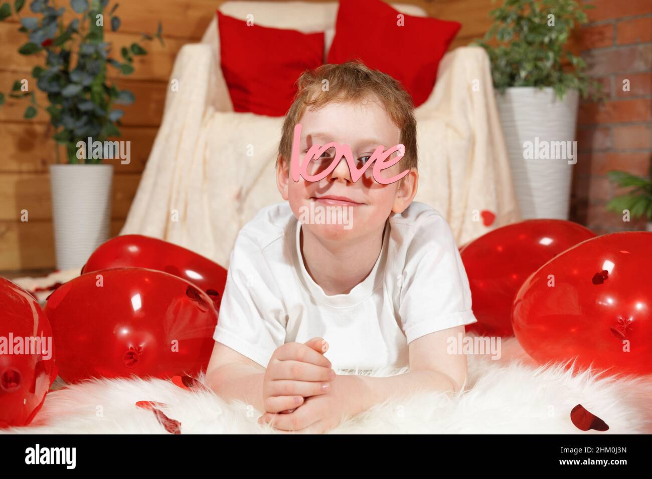 Valentinstag Kinder oder Kinder. Niedlichen fröhlichen kleinen Jungen mit roten Ballons in Form eines Herzens und Text Liebe in Form einer Brille, auf Valentine' Stockfoto