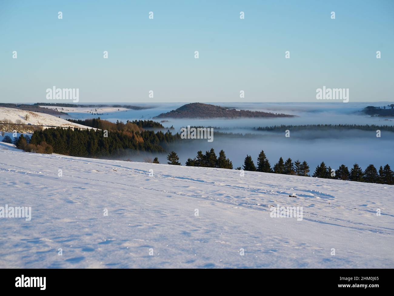 Das Konzept der Entspannung in den Bergen im Winter im Schnee auf Skiern, Snowboards oder Schlitten, Wandern unter der untergehenden Sonne bei Sonnenuntergang auf der Stockfoto