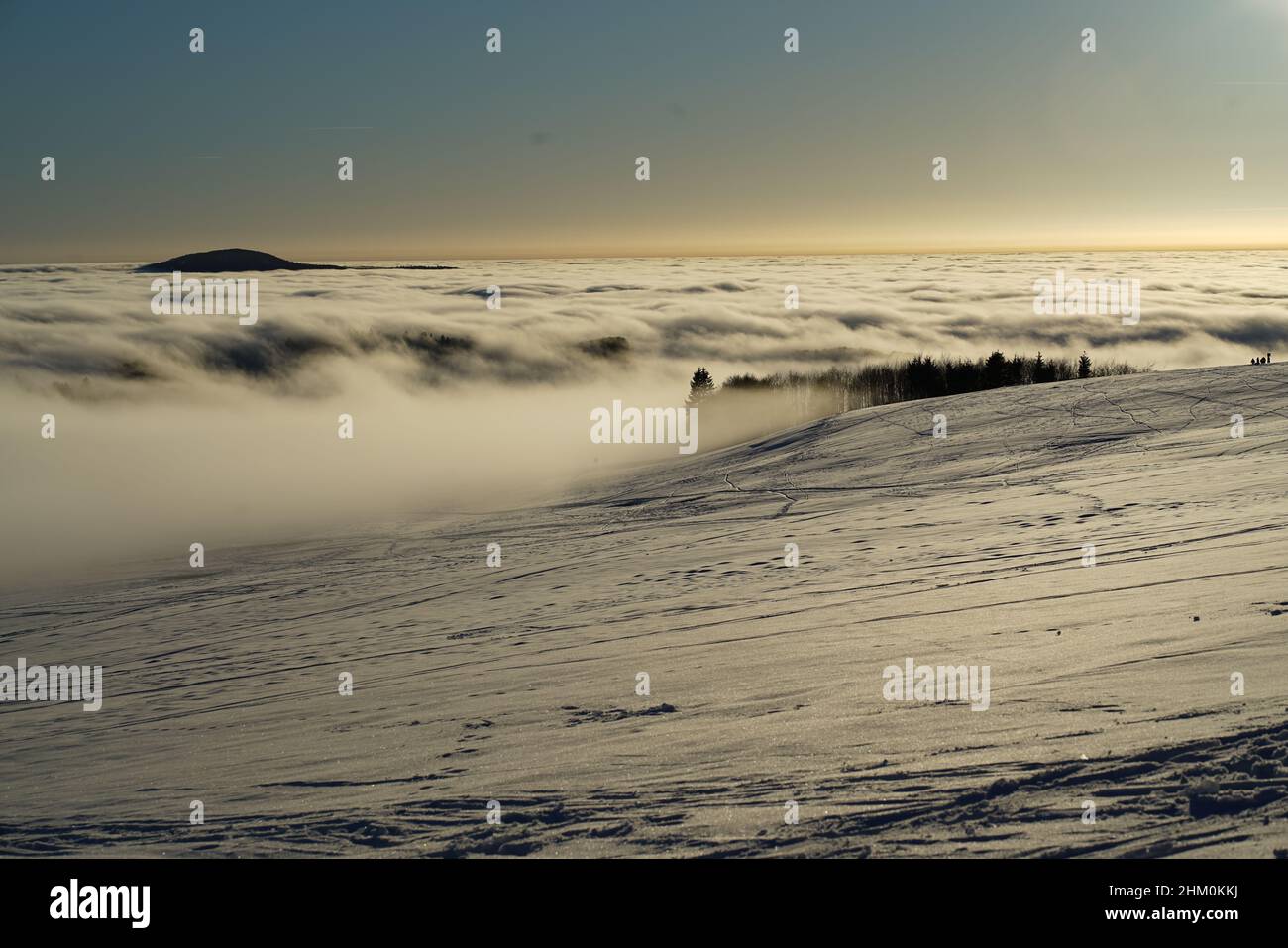 Das Konzept der Entspannung in den Bergen im Winter im Schnee auf Skiern, Snowboards oder Schlitten, Wandern unter der untergehenden Sonne bei Sonnenuntergang auf der Stockfoto