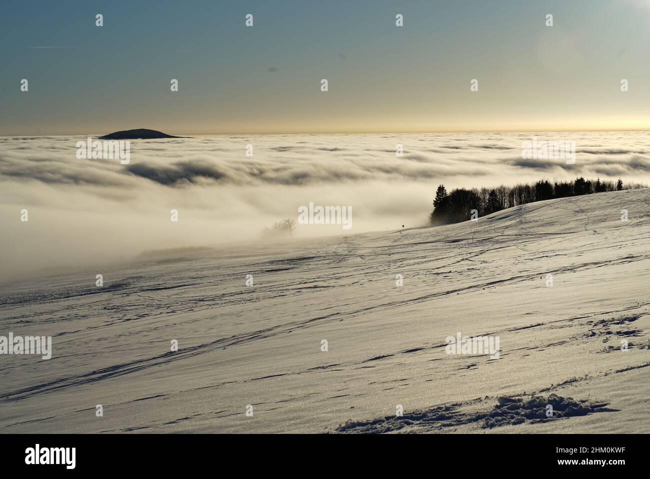Das Konzept der Entspannung in den Bergen im Winter im Schnee auf Skiern, Snowboards oder Schlitten, Wandern unter der untergehenden Sonne bei Sonnenuntergang auf der Stockfoto