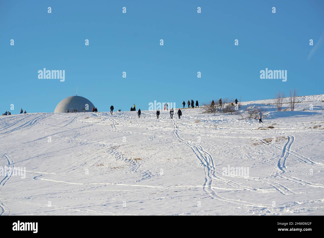 Das Konzept der Entspannung in den Bergen im Winter im Schnee auf Skiern, Snowboards oder Schlitten, Wandern unter der untergehenden Sonne bei Sonnenuntergang auf der Stockfoto