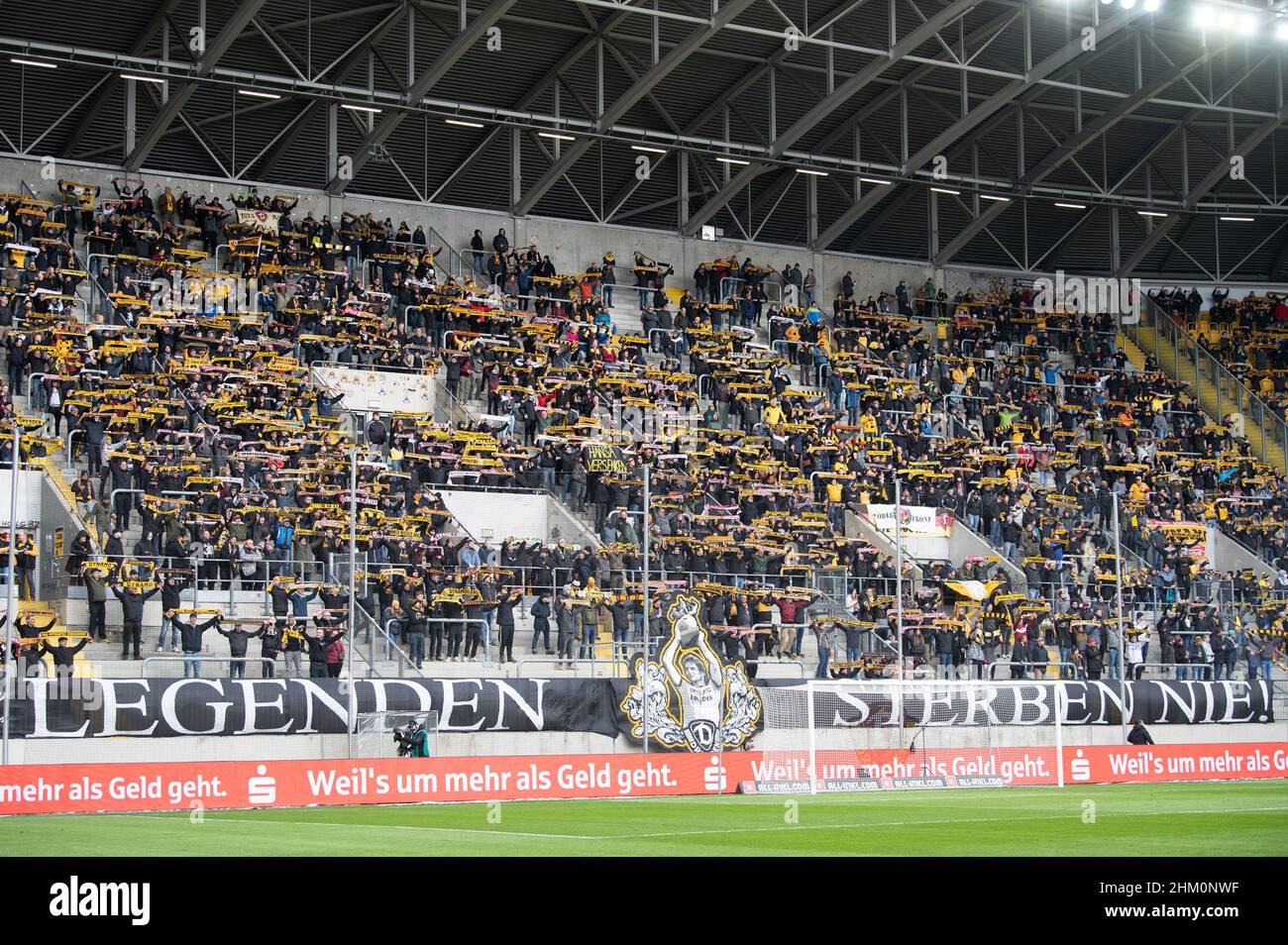 06. Februar 2022, Sachsen, Dresden: Fußball: 2nd Bundesliga, Dynamo Dresden - Hansa Rostock, Matchday 21 im Rudolf-Harbig-Stadion: Dynamo Dresden-Fans stehen auf den Tribünen vor dem Spiel hinter einem Transparent mit der Aufschrift „Legenden sterben nie“. Foto: Sebastian Kahnert/dpa-Zentralbild/dpa - WICHTIGER HINWEIS: Gemäß den Anforderungen der DFL Deutsche Fußball Liga und des DFB Deutscher Fußball-Bund ist es untersagt, im Stadion und/oder vom Spiel aufgenommene Fotos in Form von Sequenzbildern und/oder videoähnlichen Fotoserien zu verwenden oder zu verwenden. Stockfoto