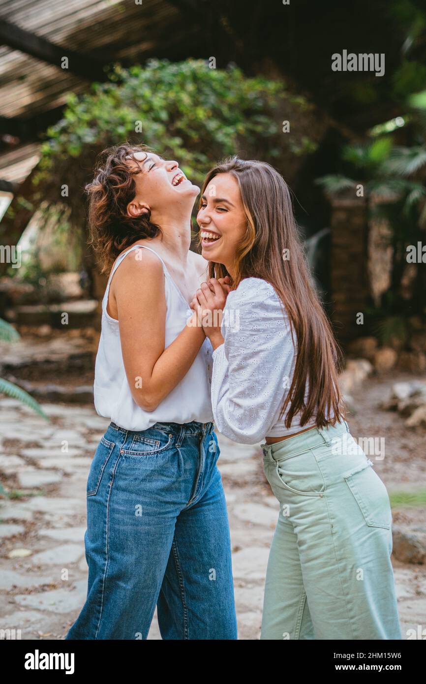 Zwei junge Teenager Freundinnen lachen umgeben von Pflanzen Stockfoto