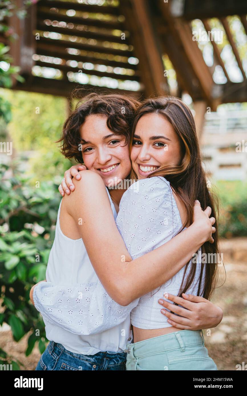 Zwei junge Teenager-Mädchen umarmten sich und lächelten, umgeben von Pflanzen. Stockfoto