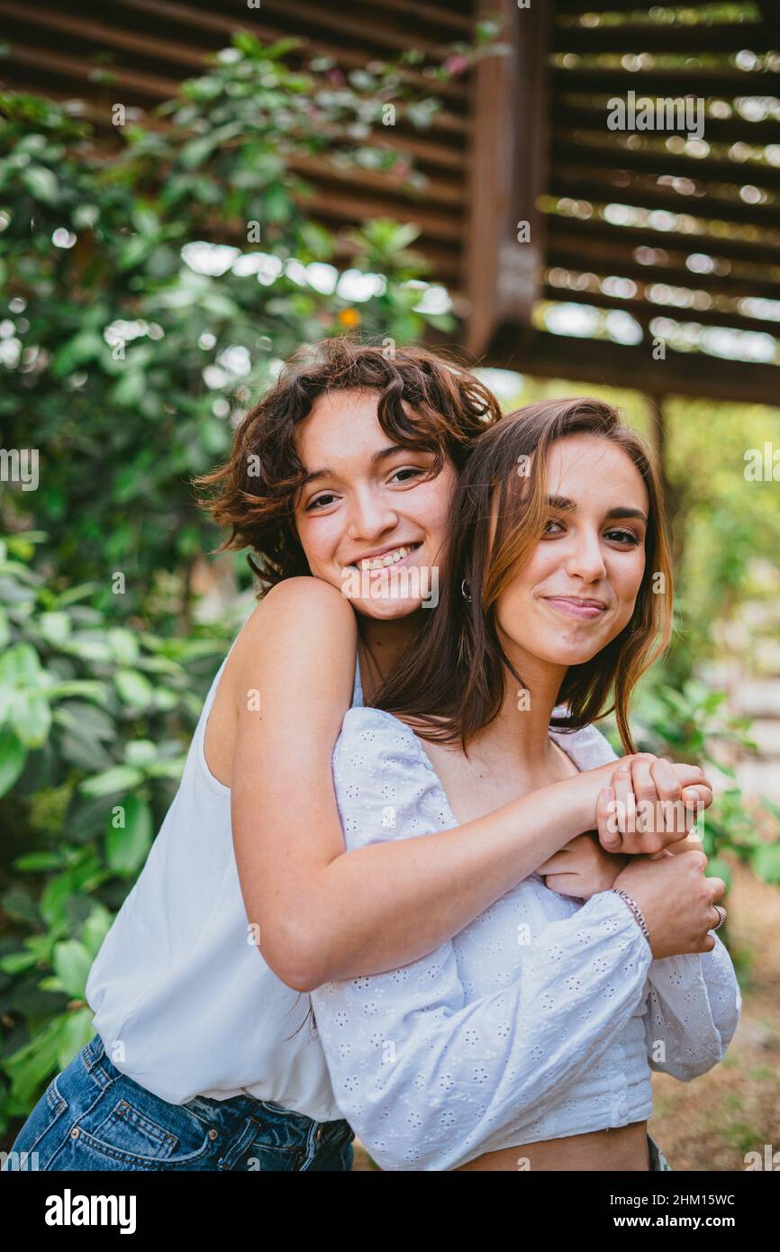 Zwei junge Teenager-Mädchen umarmten sich und lächelten, umgeben von Pflanzen. Stockfoto