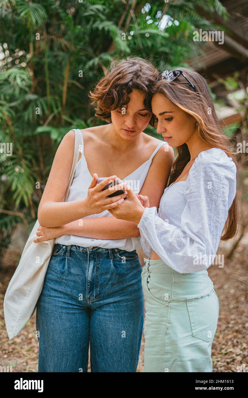 Zwei Teenager-Mädchen, die auf ein Mobiltelefon blicken. Sie sind Freunde und schauen sich eine Botschaft an. Stockfoto