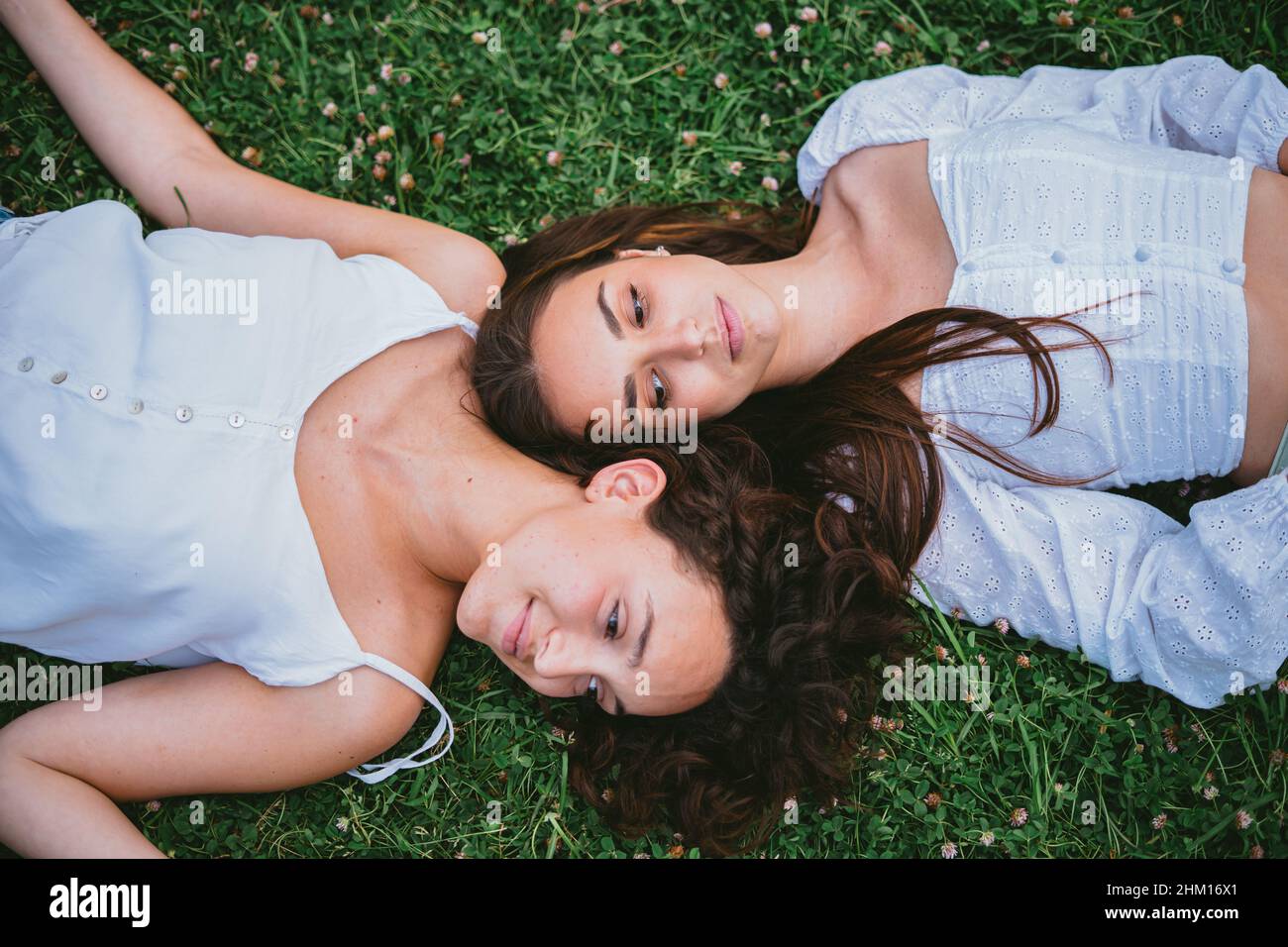 Zwei entspannte Mädchen, die sich in einem Park auf dem Rasen niederlegen, während sie sich ausruhen Stockfoto