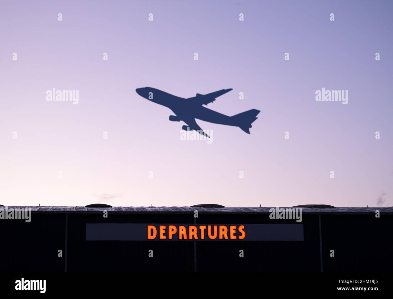 Ein Flugzeug, Das Bei Sonnenuntergang Abfliegt, Mit Dem Abfluggebäude Des Flughafens Im Vordergrund Stockfoto