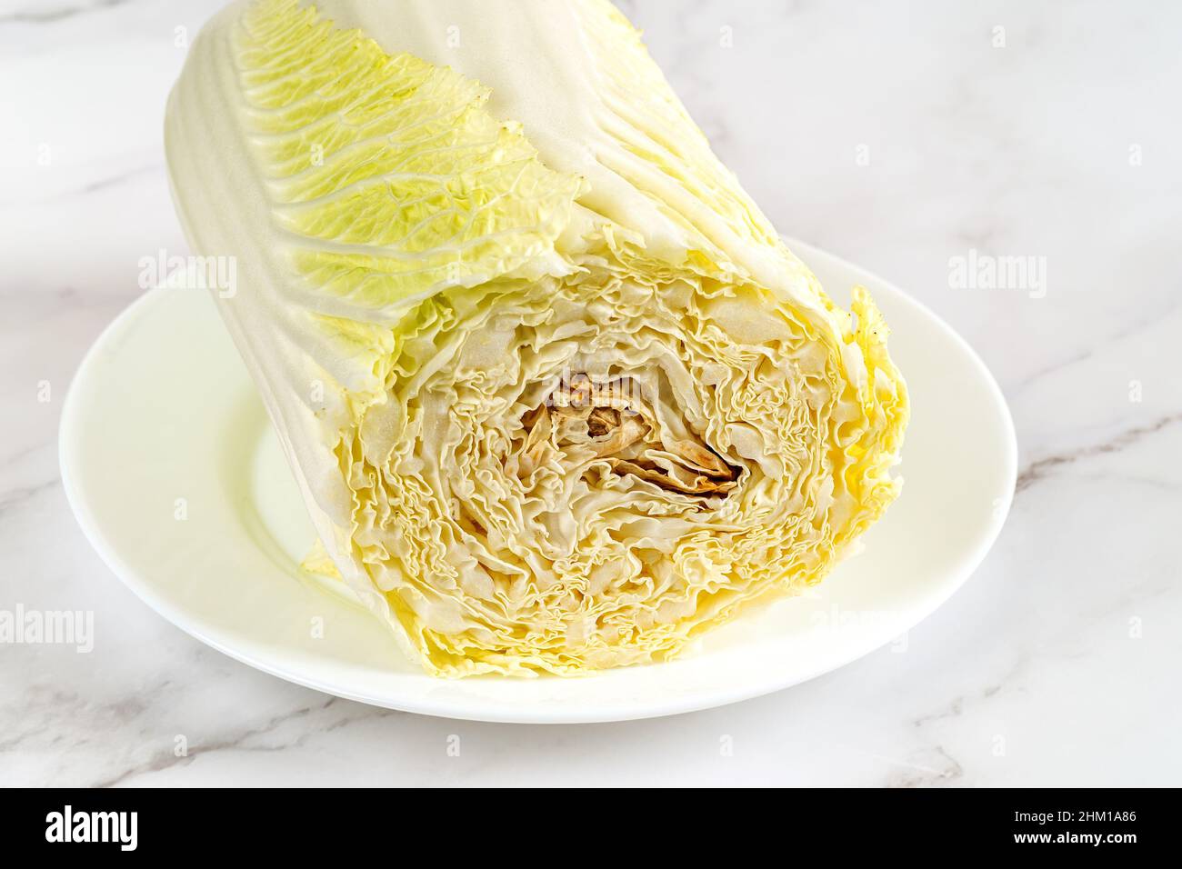 Verfaulte napa Kohl auf einem Teller. Der Kohlkopf verdirbt von innen. Die Fäulnis in einem frischen chinesischen Kohl. Lebensmittelabfälle und verdorbenes Gemüse. Stockfoto