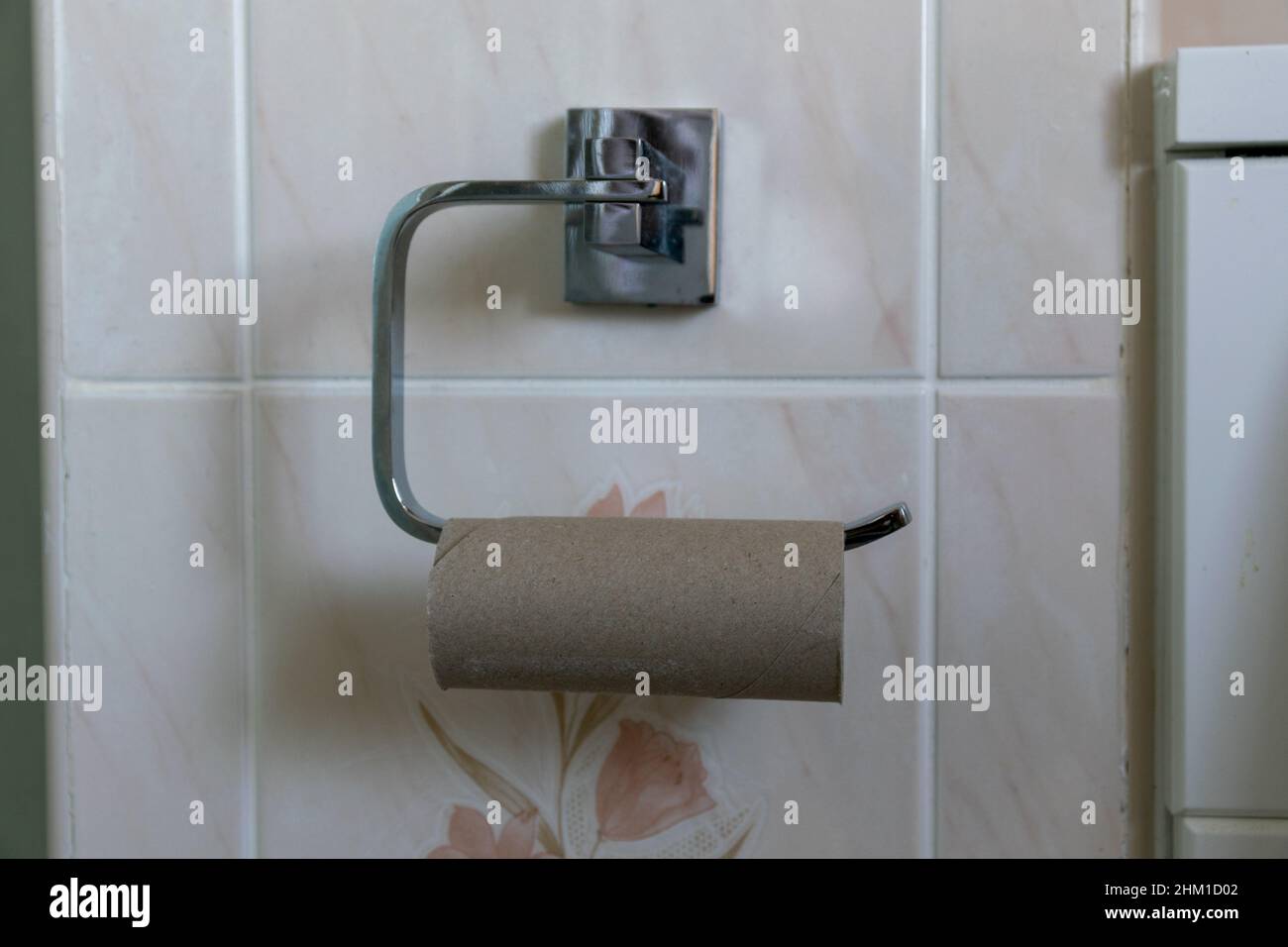 Leeres Toilettenpapierkartonrohr auf Metall-Toilettenpapierhalter. Stockfoto