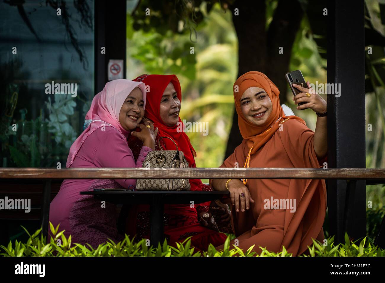 Yala, Thailand. 06th. Februar 2022. Muslimische Frauen nehmen Selfies ab, während sie auf Kaffee im Geschäft in der Provinz Yala, Thailand, warten.tägliches Leben in der Provinz Yala, an der thailändisch-malaysischen Grenze an der Ostküste der malaiischen Halbinsel, ist Yala die südlichste Provinz Thailands und das Verwaltungszentrum der Region des tiefen Südens. Aufgrund der Gewalt religiöser und separatistischer Aufständischer steht Yala seit über einem Jahrzehnt unter einem Notdekret. (Foto von Matt Hunt/SOPA Images/Sipa USA) Quelle: SIPA USA/Alamy Live News Stockfoto