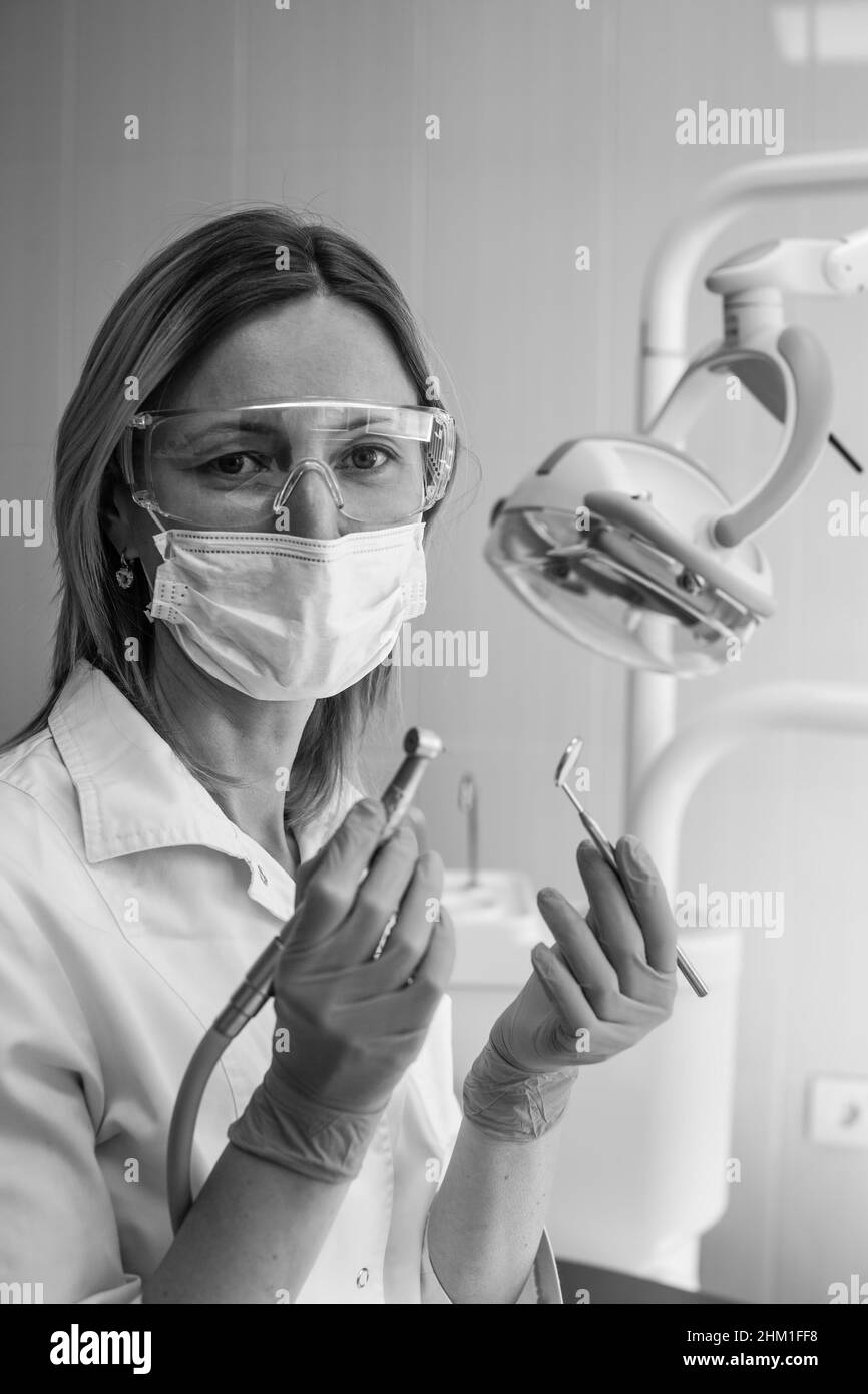 Weibliche Zahnärztin hält ein Werkzeug in der Zahnklinik. Schwarzweiß-Foto. Stockfoto