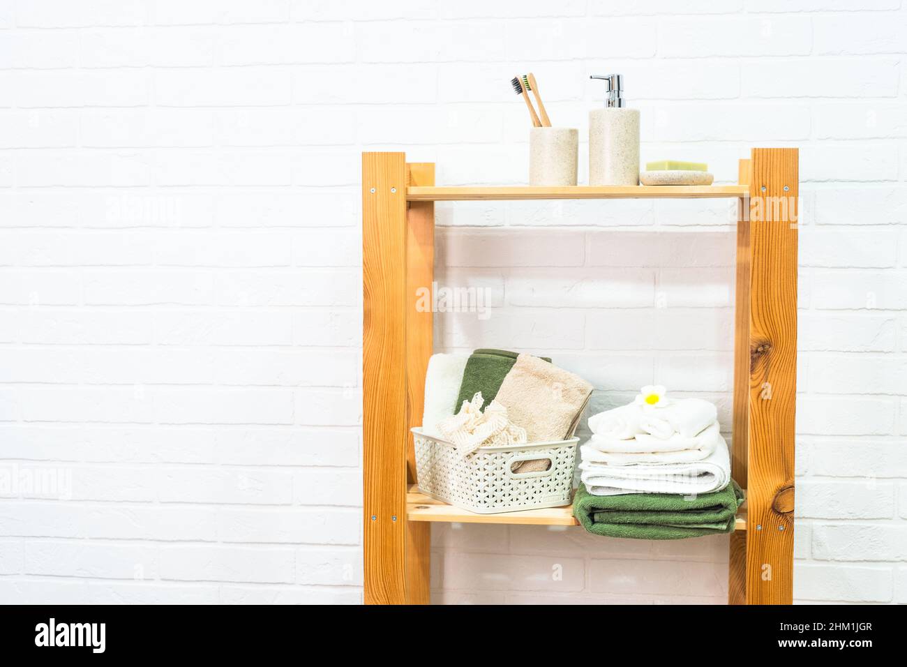 Badezimmer mit Holzregalen für Kosmetikprodukte und Handtücher. Stockfoto