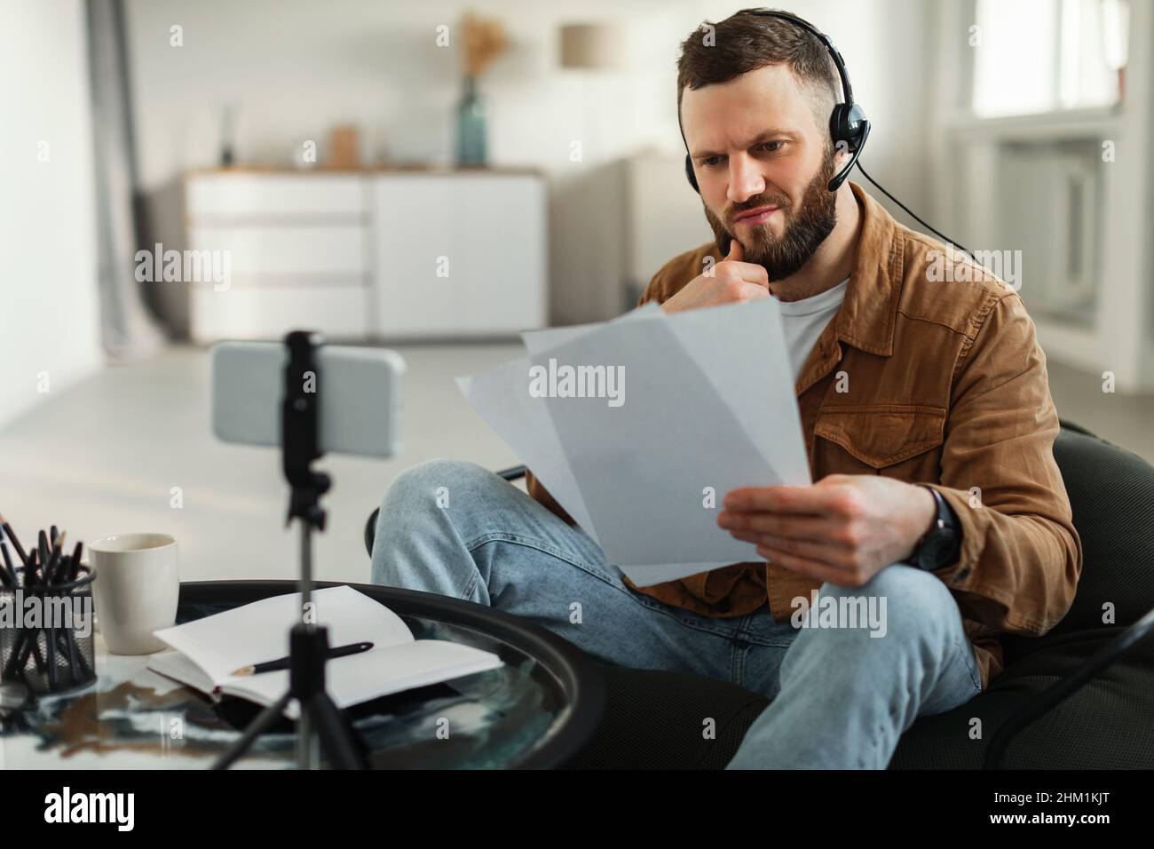 Mann Liest Papiere Videoanrufe Über Smartphone Zu Hause Stockfoto