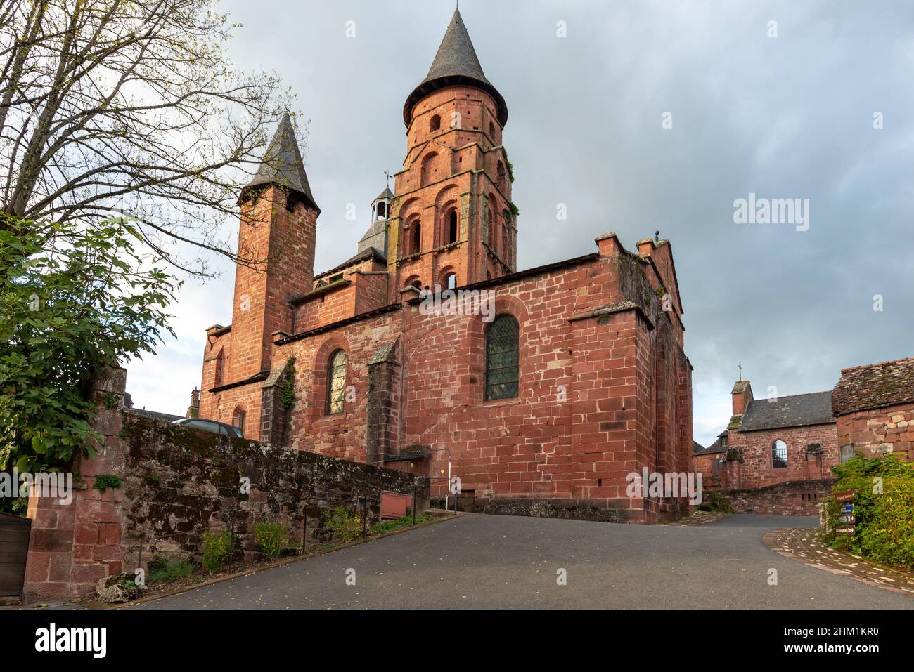Eine malerische und verschlungene römische Steinkirche in Collonges-la-Rouge, Correze, Frankreich, aufgenommen an einem teilweise sonnigen Herbstnachmittag ohne Menschen. Stockfoto
