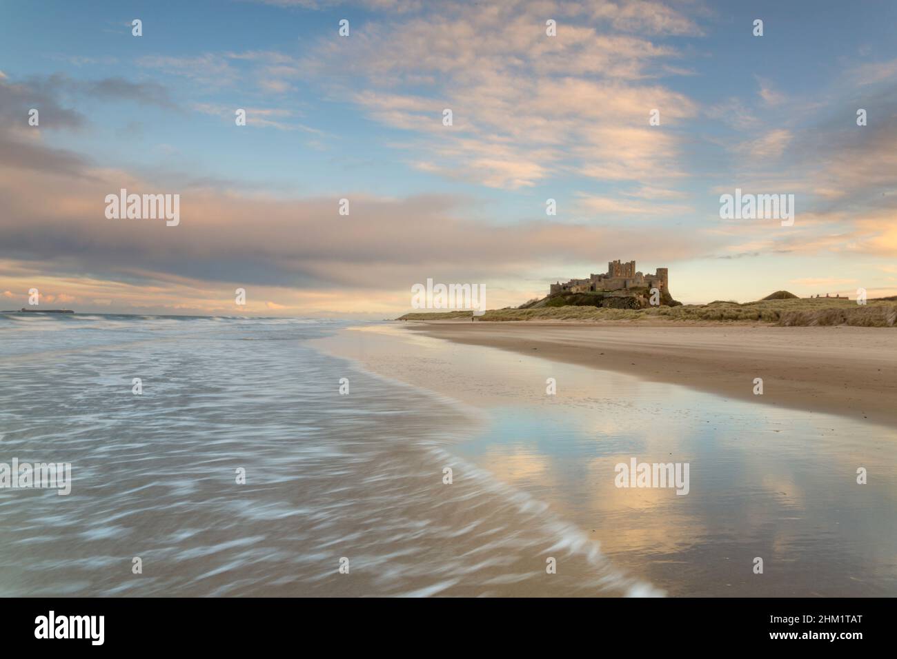 Sonnenuntergang bei Flut am Bamburgh Strand und Schloss an der Northumberland Küste, Nordostengland im Winter Stockfoto