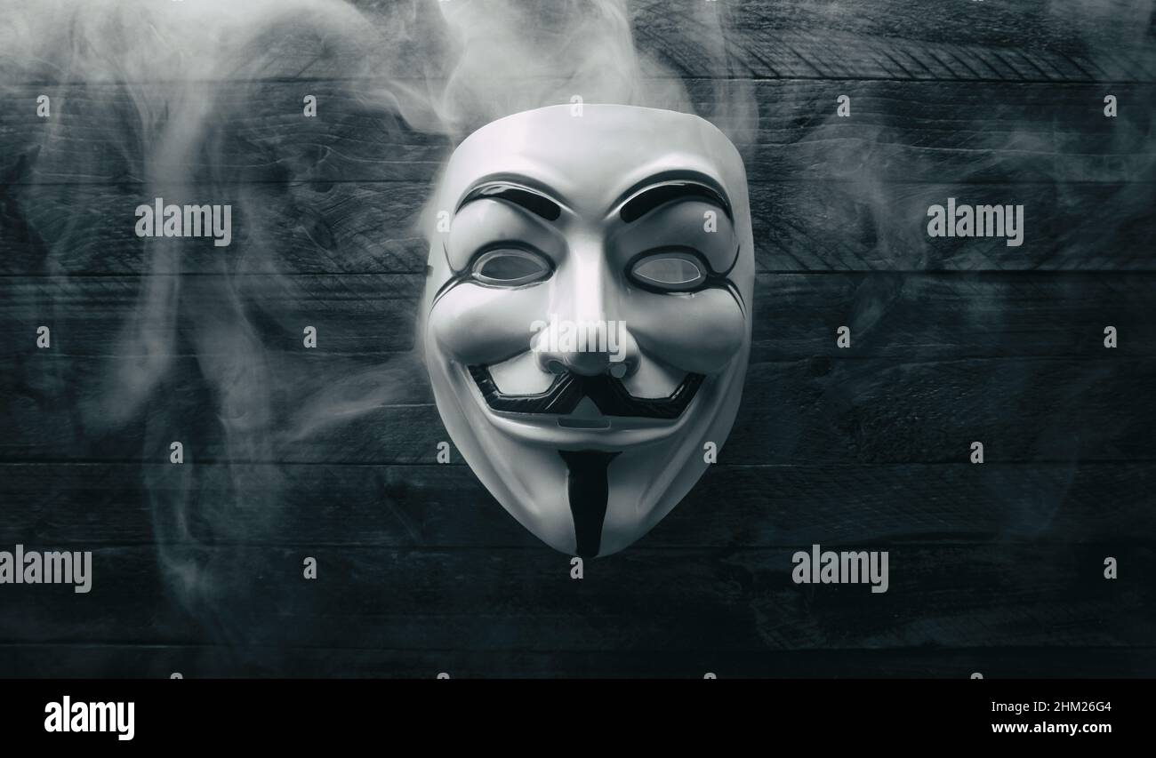 Studioaufnahme einer Maske der Anonymen Vendetta mit Rauch auf Holz Stockfoto