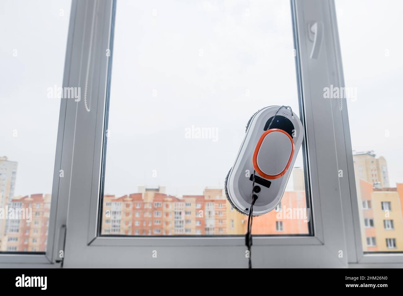 Roboter-Fensterputzer arbeiten an schmutzigen Fenstern. Reinigung des Hauses mit intelligenten Geräten. Automatische Vakuumroboter zur Fensterreinigung, ein Assistent für den Stockfoto