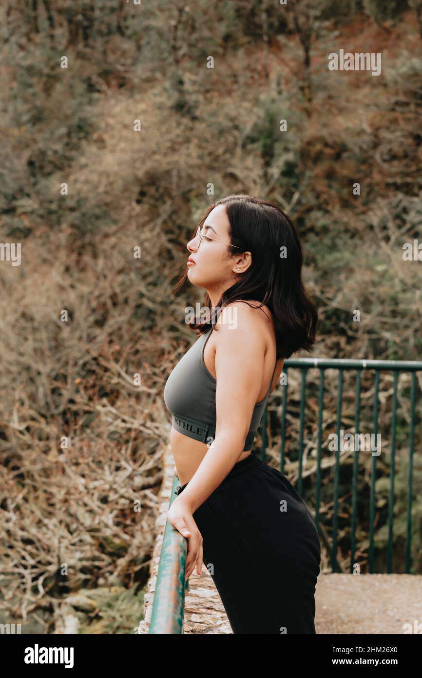 Junge arabische Frau auf Sportkleidung ruhen auf einem Bürgersteig, während der Blick auf den Horizont im Wald, während eines Herbsttages, Inspiration Bild mit Stockfoto