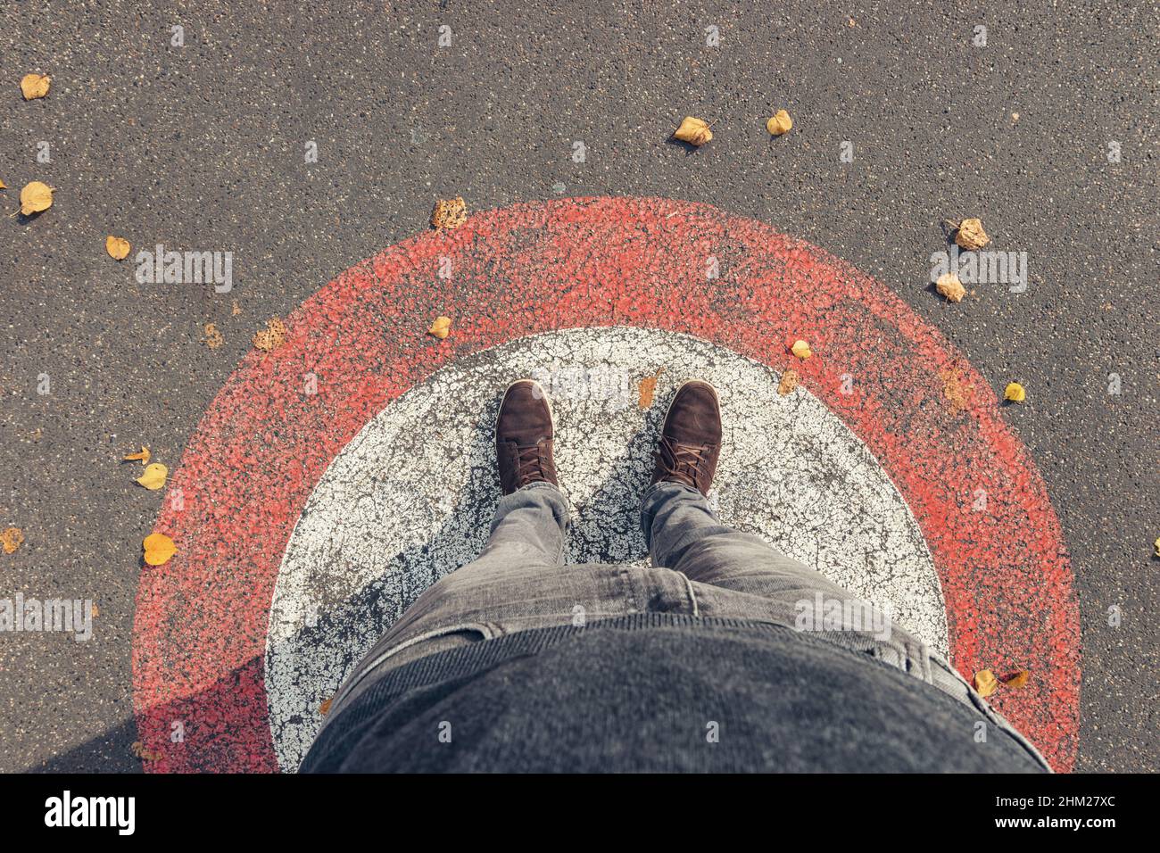 Der junge Mann steht im Herbst im Kreis auf den Straßen, persönlich pessive von oben. Stockfoto