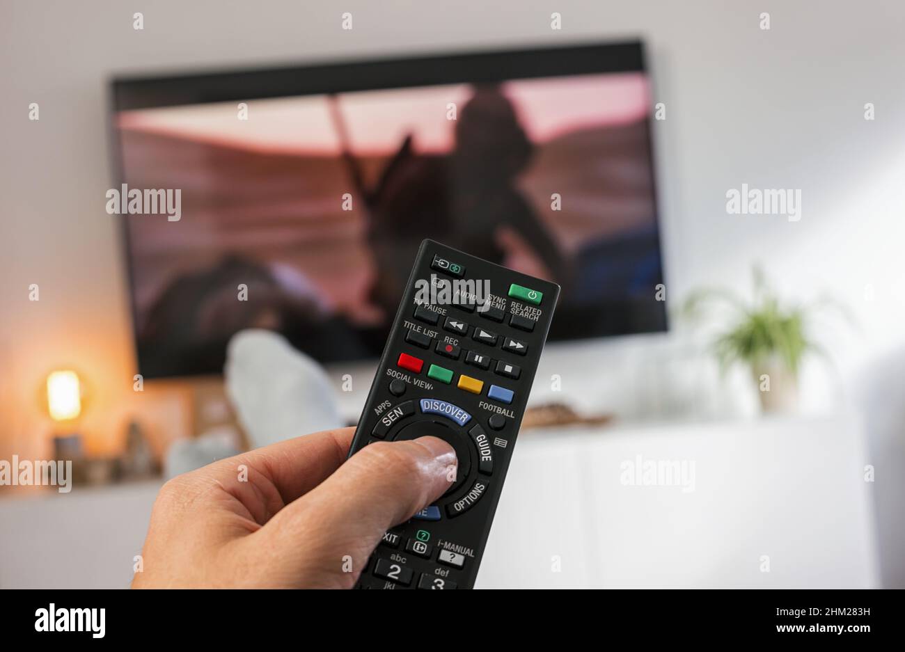 Fernbedienung und Fernsehen mit männlicher Hand Stockfoto