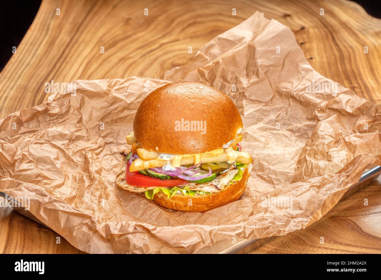 Köstlicher saftiger Burger mit Rauch auf einem Holztisch Stockfoto