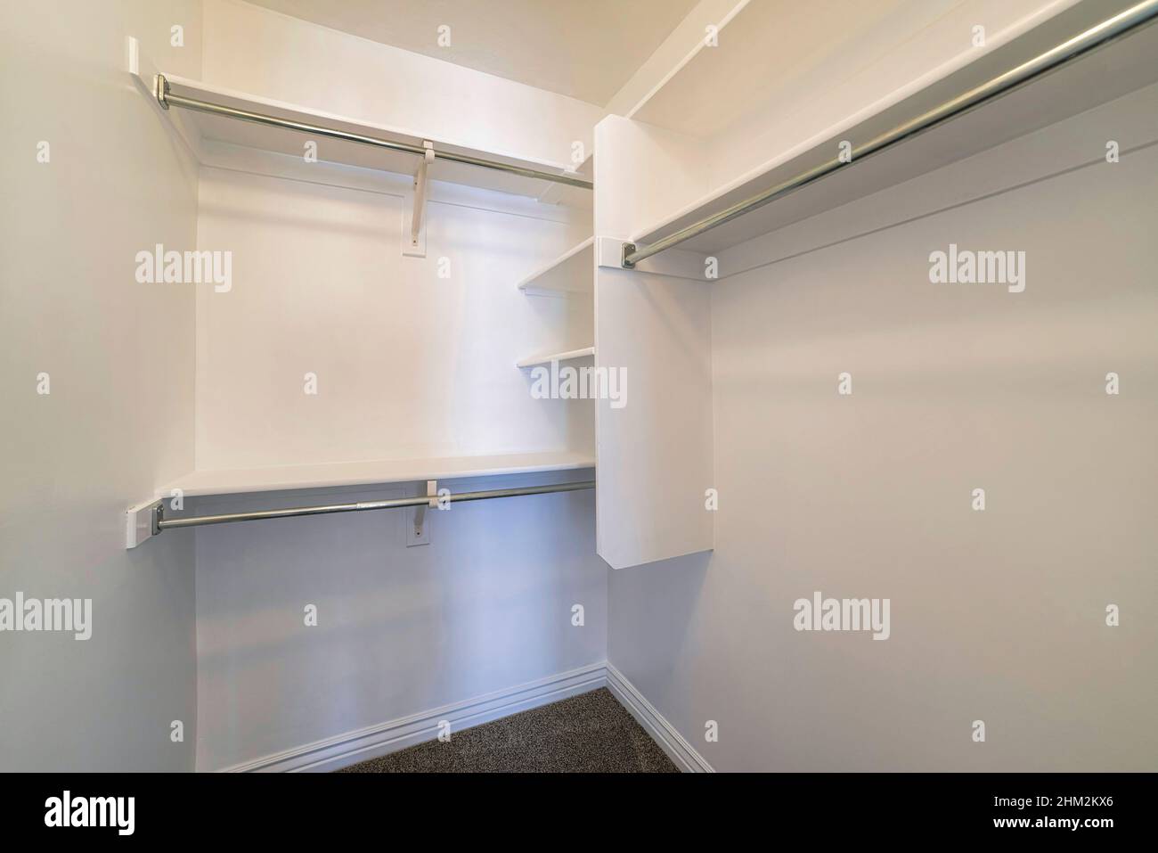 Kleiner begehbarer Kleiderschrank mit vertikalen Regalen in der Ecke Stockfoto