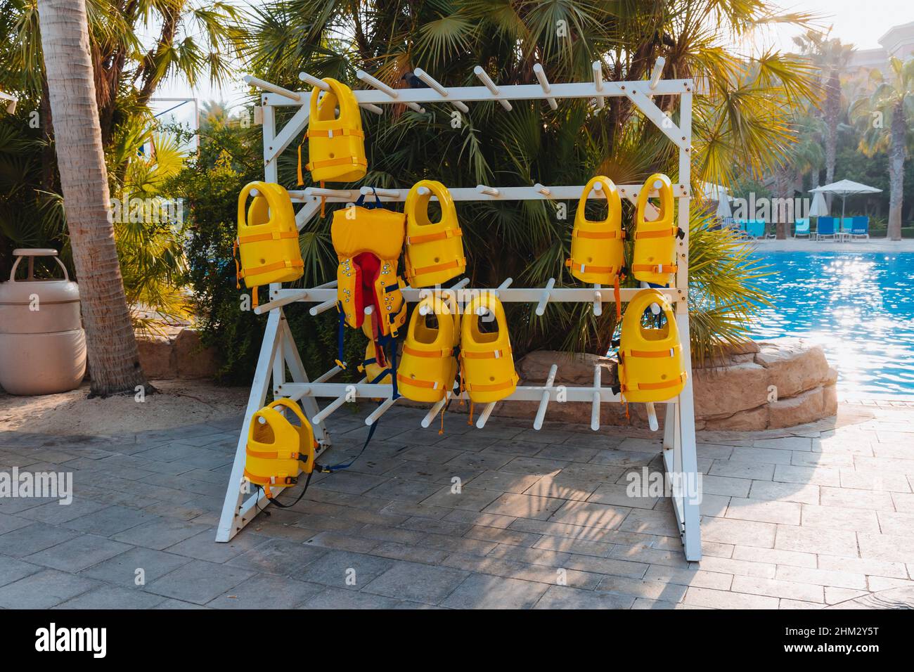 Stapel von hängenden gelben Rettungswesten auf Kleiderbügeln draußen während der Marine-Aktivitäten, Sicherheitskleidung, Schutzkonzept. Stockfoto