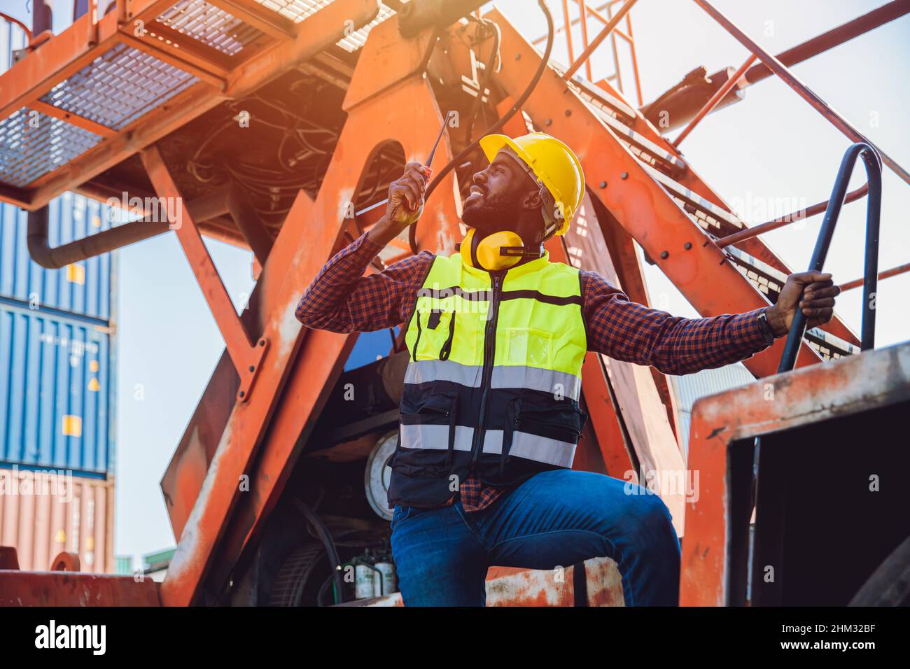 Schwarzer afrikanischer Arbeiter arbeitet als Hafenfrachtmanager, der in der Logistikindustrie per Funksteuerung Ladecontainer verwendet. Stockfoto