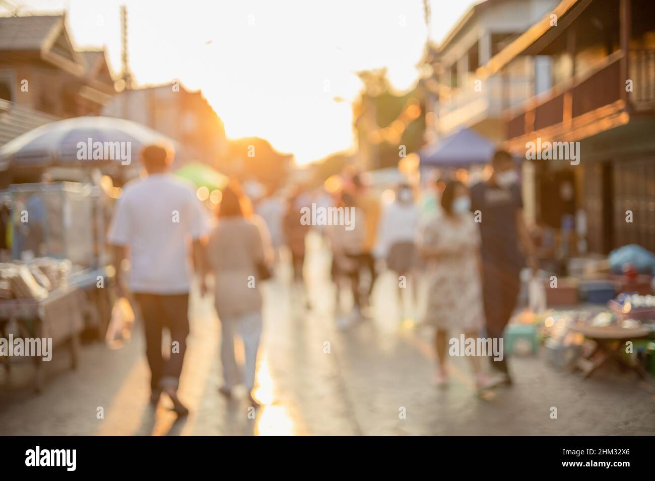 Verwischen Sie Menschen, die in der Einkaufsstraße spazieren gehen Sonnenuntergang schönes Licht für den Hintergrund Stockfoto