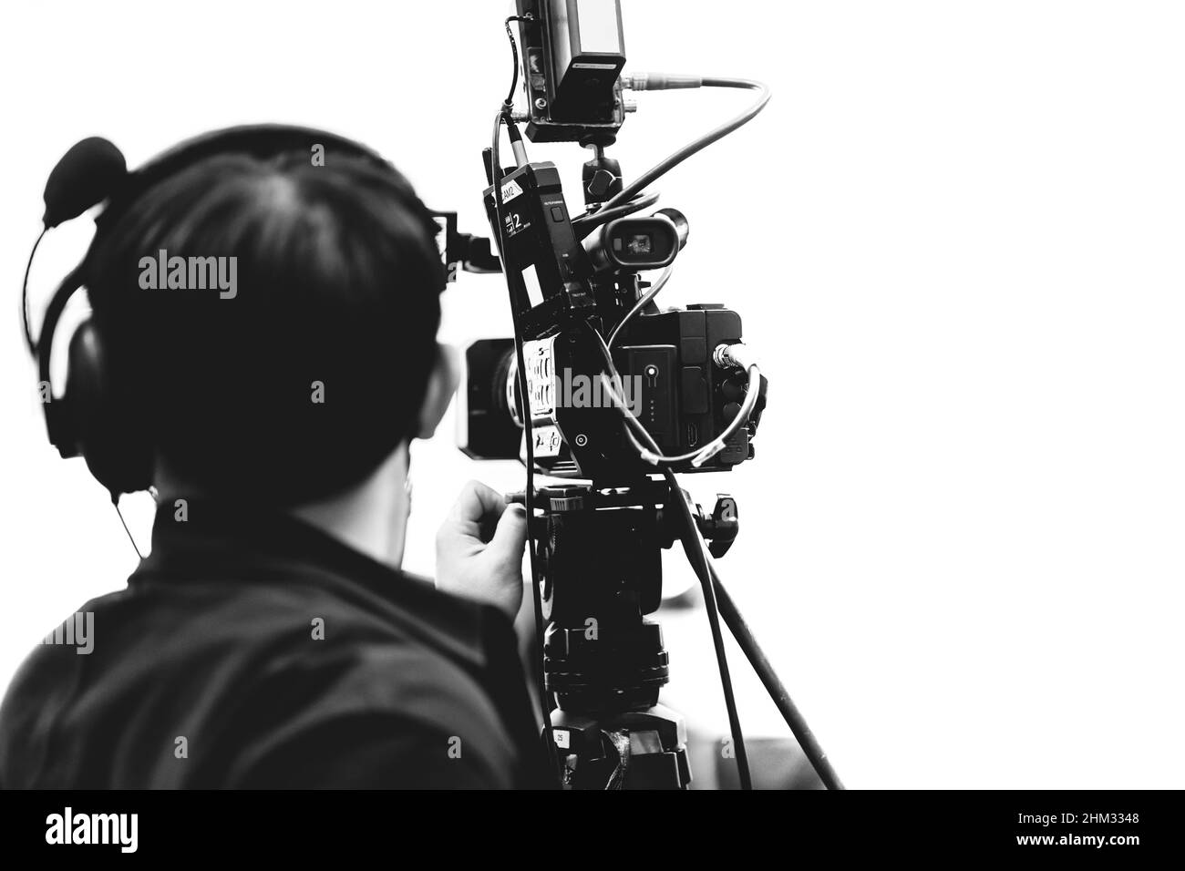 Kameramann mit professionellem Video-Camcorder in der Medienbranche, schwarz auf weiß Stockfoto