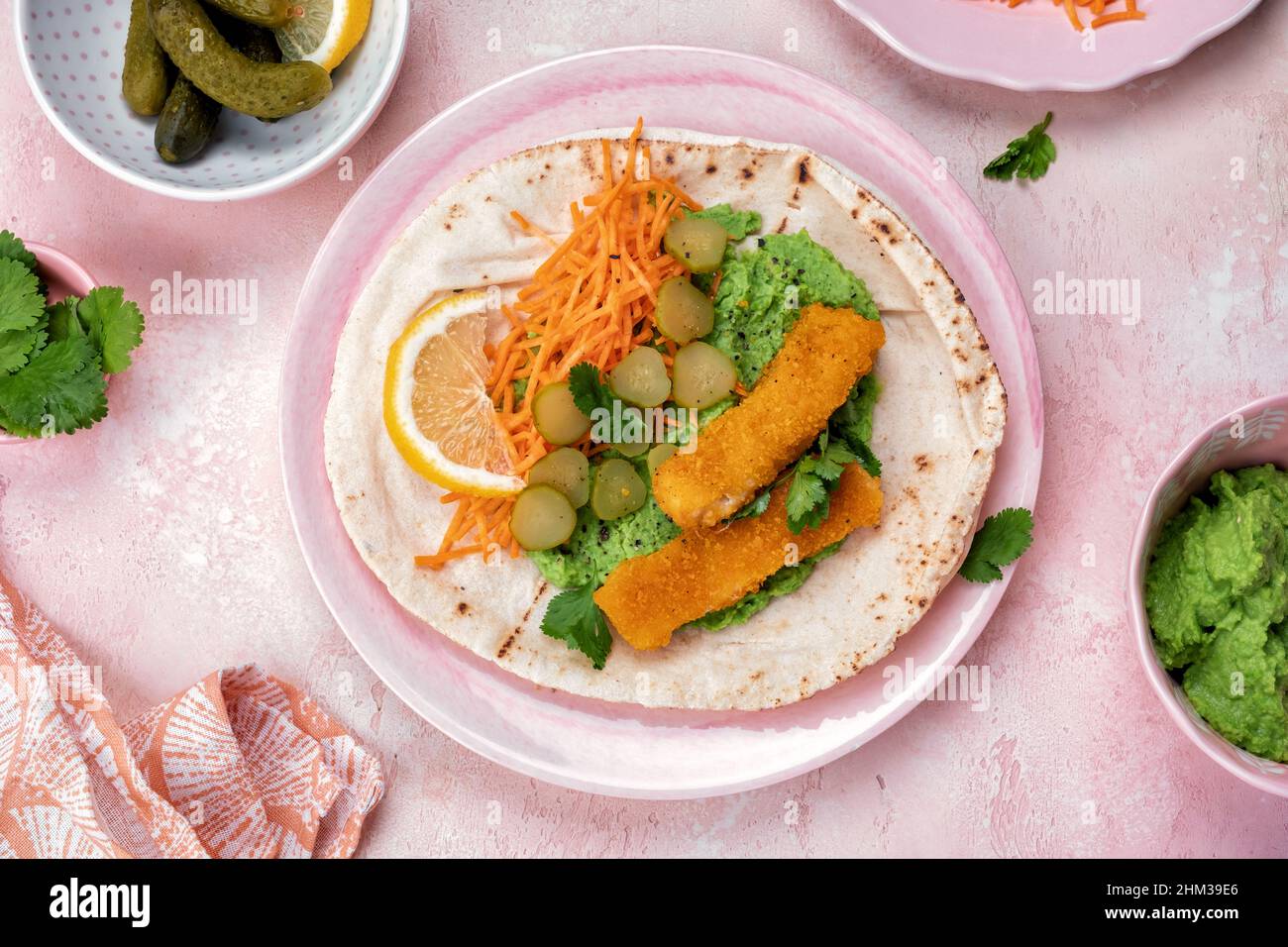 Fischfinger umhüllt mit Erbsenpüree und Gemüse in Tortilla Stockfoto