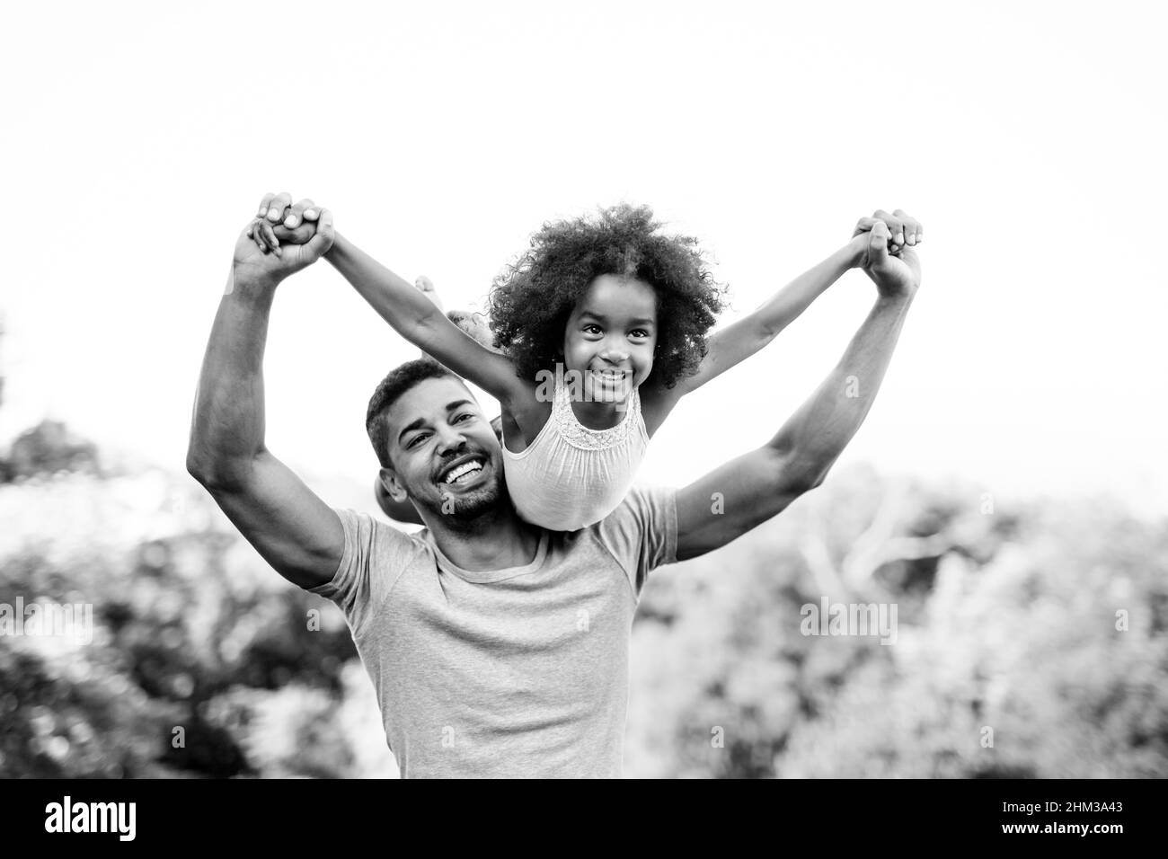 Porträt eines glücklichen schwarzen Vaters, der seine Tochter auf dem Rücken im Freien trägt. Familie Glück Liebe Konzept. Stockfoto