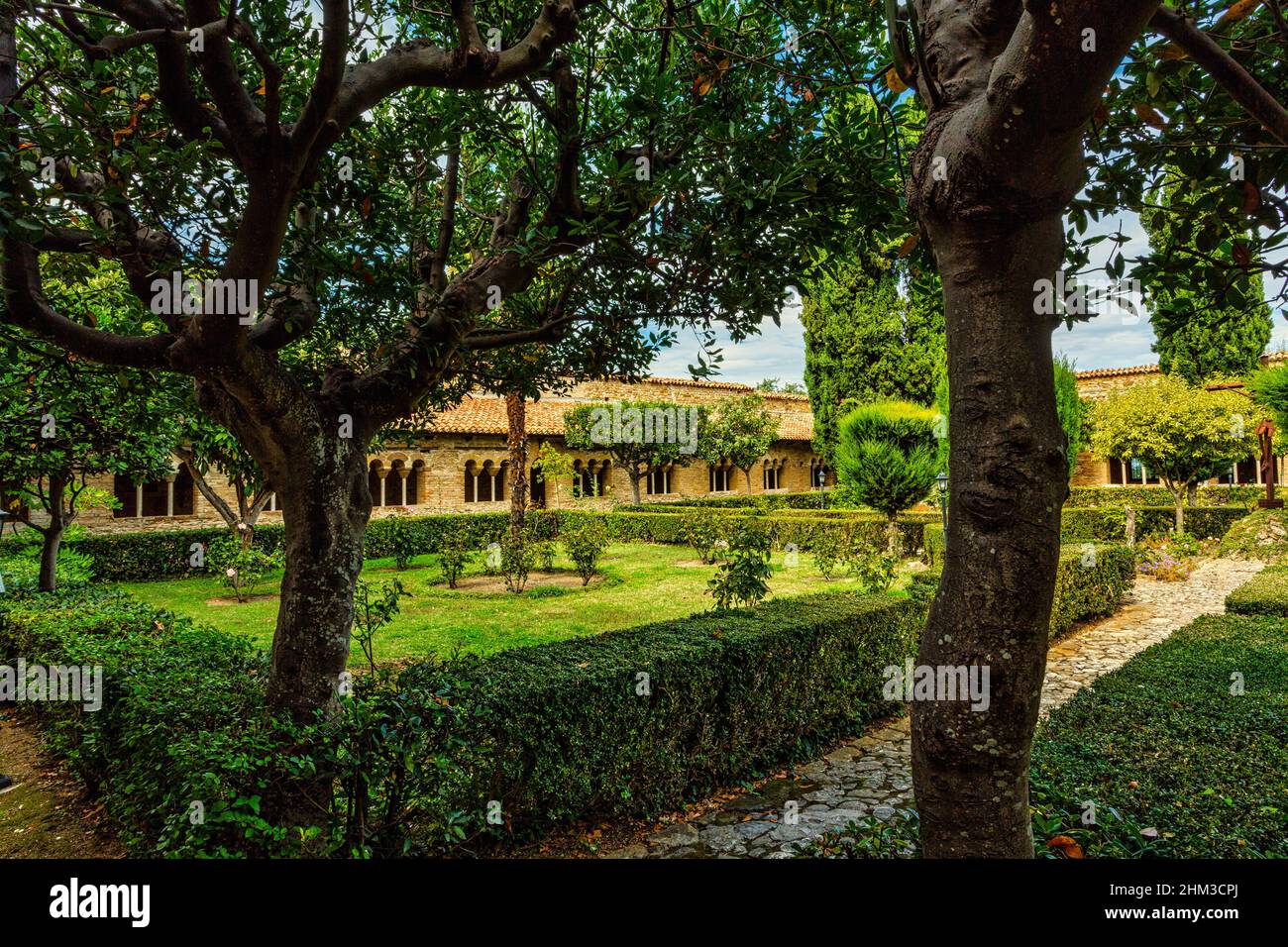 Innenansicht der Gärten der Abtei von San Giovanni in Venere mit schönen geformten Bäumen, grünen Heckenund Kreuzgang Gebäude.Fossacesia, Abruzzen Stockfoto