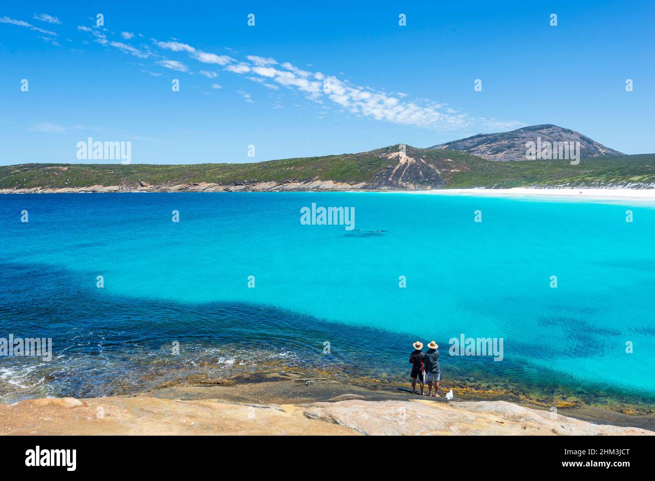 Zwei Personen beobachten eine Gruppe von Delfinen an der berühmten Hellfire Bay, Cape Le Grand, in der Nähe von Esperance, Western Australia, WA, Australien Stockfoto