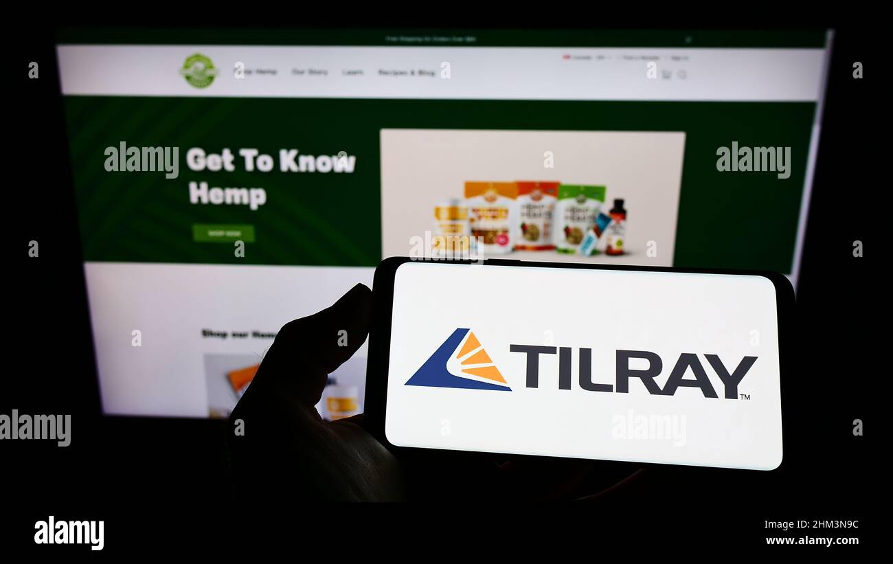 Person, die Mobiltelefon mit dem Logo des kanadischen Cannabisunternehmens Tilray Inc. Auf dem Bildschirm vor der Business-Webseite hält. Konzentrieren Sie sich auf die Telefonanzeige. Stockfoto