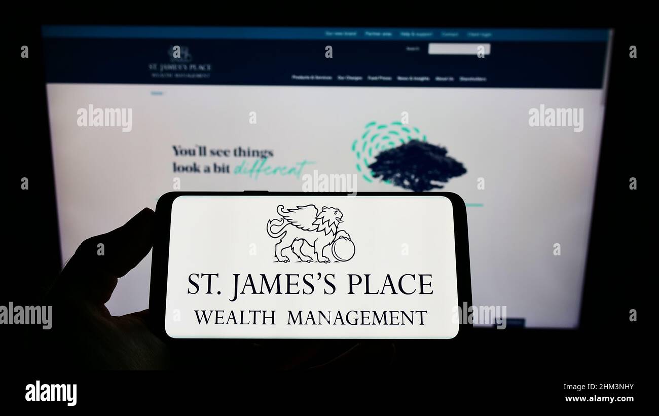 Person, die ein Smartphone mit dem Logo der britischen Firma St. James's Place plc auf dem Bildschirm vor der Website hält. Konzentrieren Sie sich auf die Telefonanzeige. Stockfoto