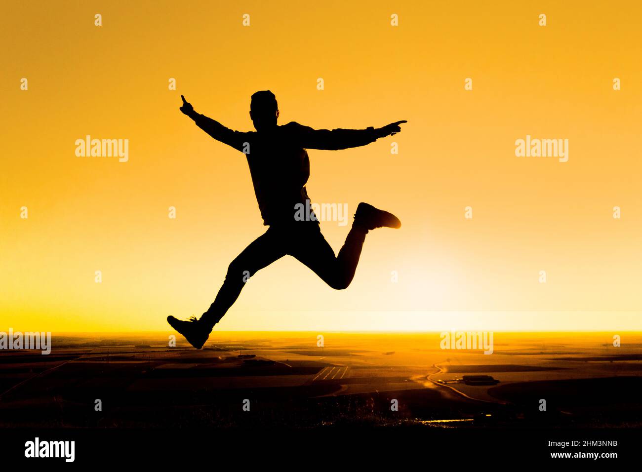 Silhouette einer Person, die bei Sonnenuntergang springt. Freiheit und Freude Stockfoto