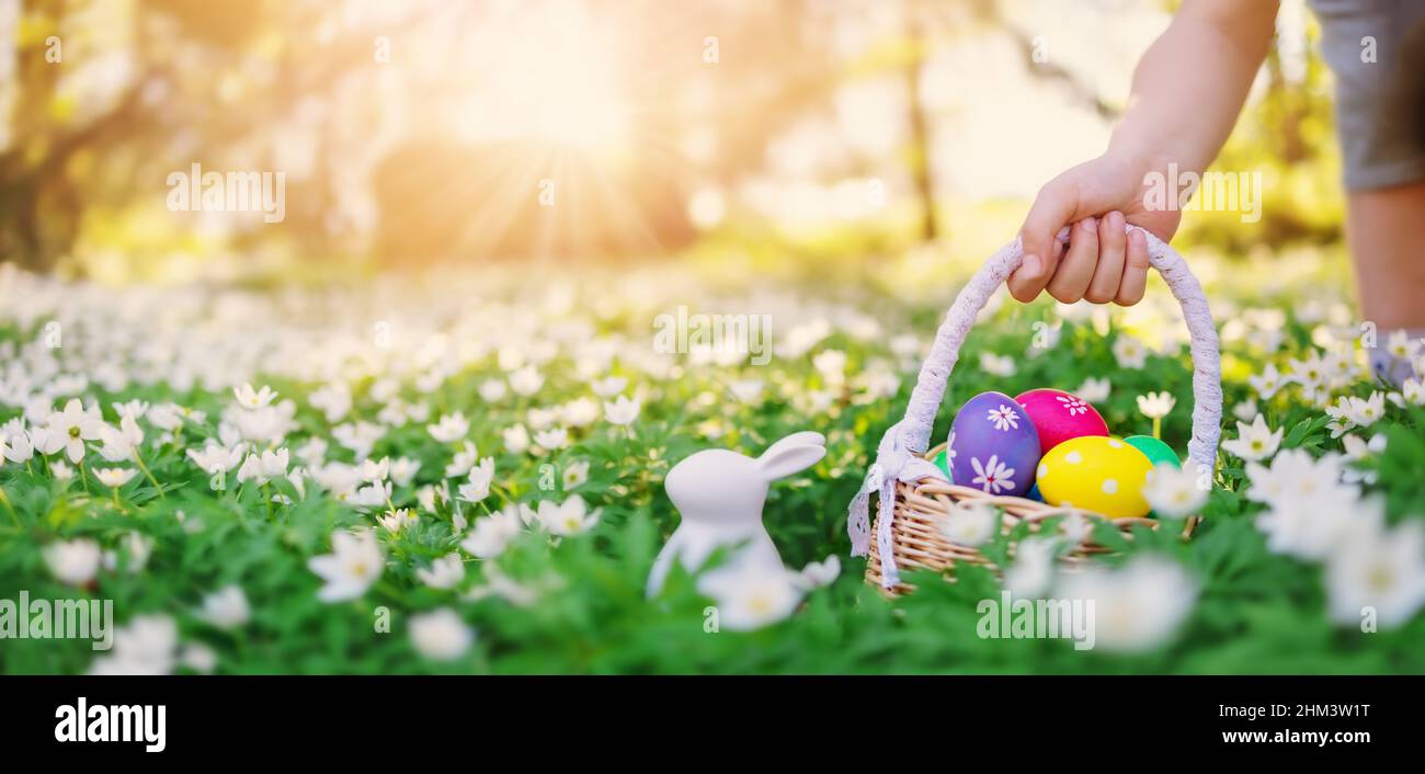 Kind hält in der Hand ein Becken mit bunten Eiern. Stockfoto